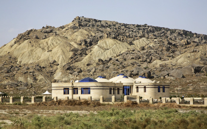 Museum building with domed roofs in Gobustan National Park, Azerbaijan, set against rocky hills.
