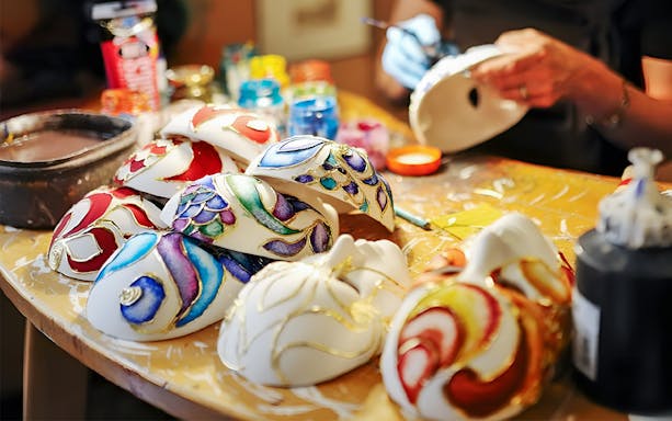 Venetian masks being painted during a glass and mask experience in Venice.