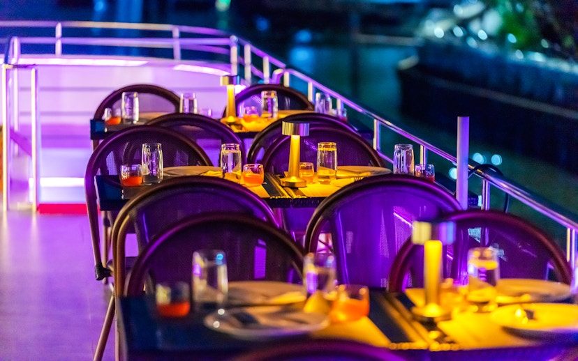 Dining setup on Bangkok Chaophraya Cruise with tables and ambient lighting.