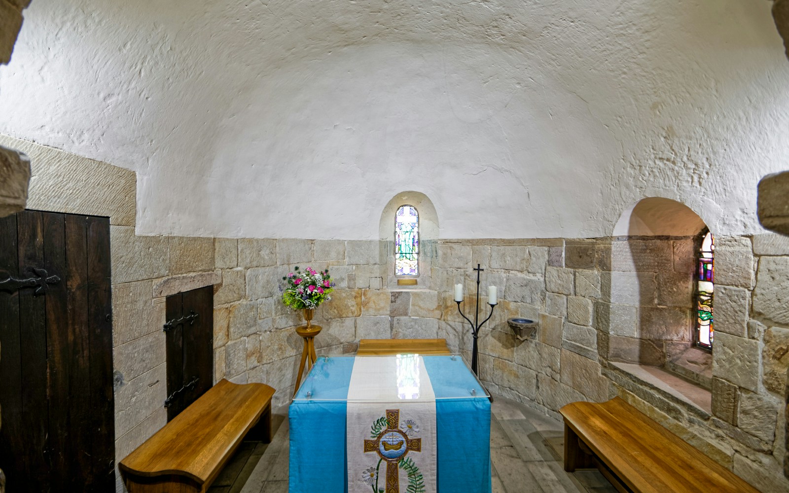 St. Margaret's Chapel interior at Edinburgh Castle, featuring altar and stained glass window.