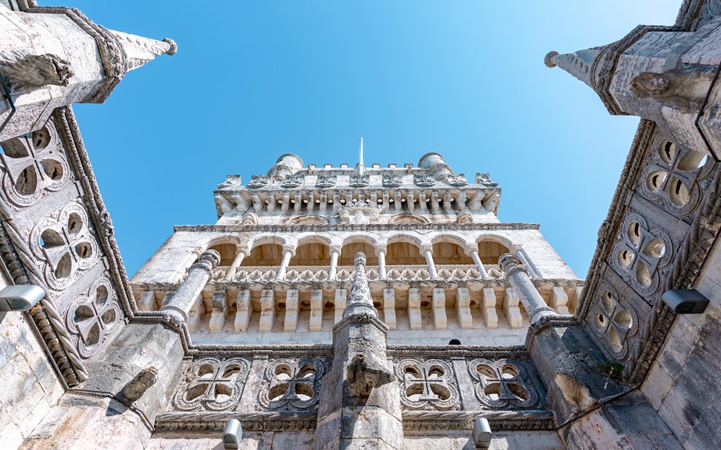 Belém Tower in Lisbon viewed from below, showcasing its ornate architecture.
