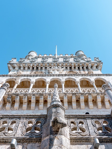 Belém Tower in Lisbon viewed from below, showcasing its ornate architecture.