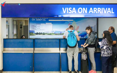 Visa on arrival counter with travelers in line at Hanoi airport, Vietnam.