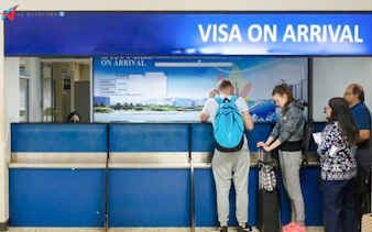 Visa on arrival counter with travelers in line at Hanoi airport, Vietnam.