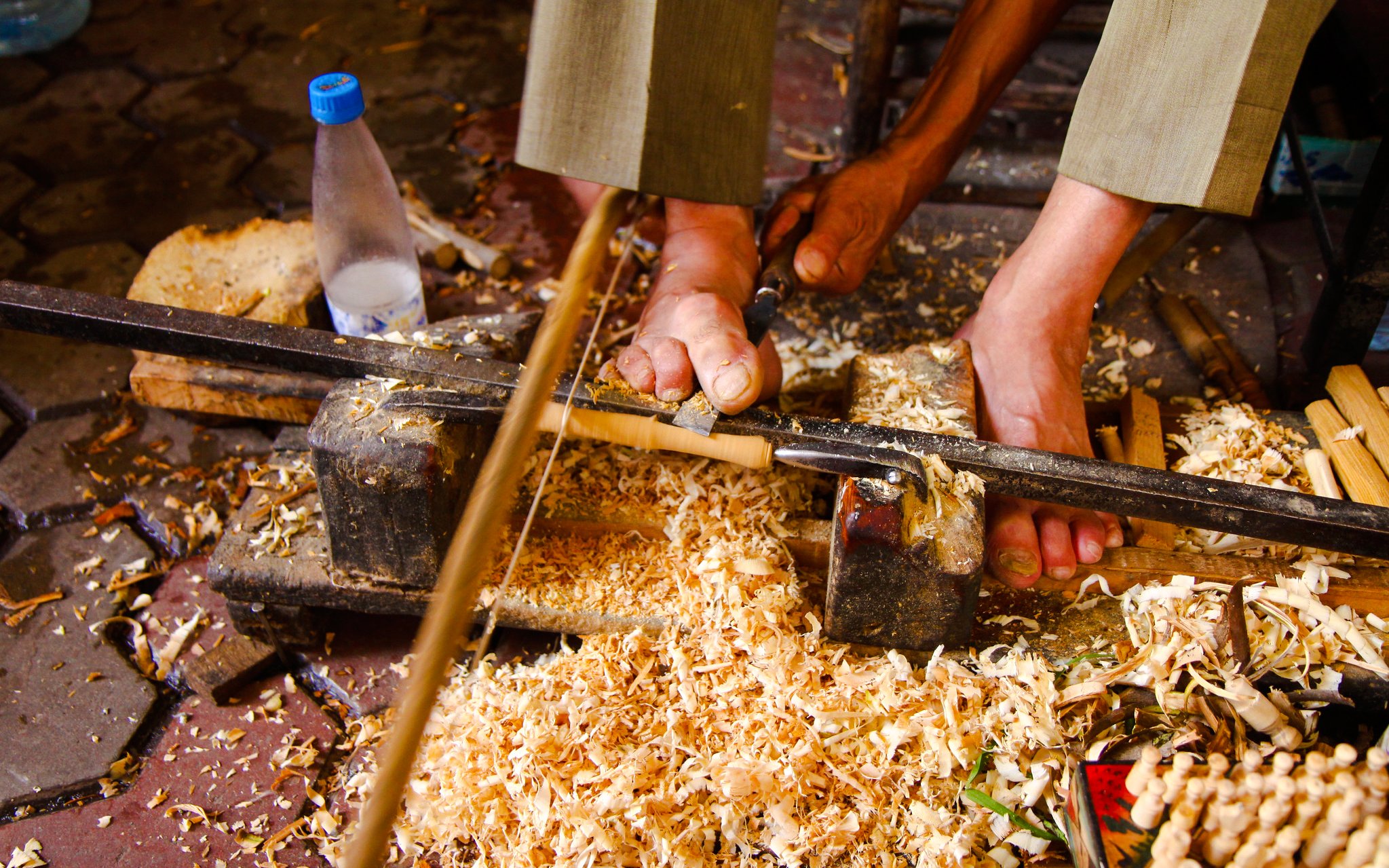 Woodworker carving with feet in Marrakech workshop.