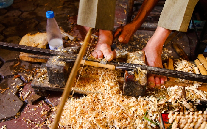 Woodworker carving with feet in Marrakech workshop.