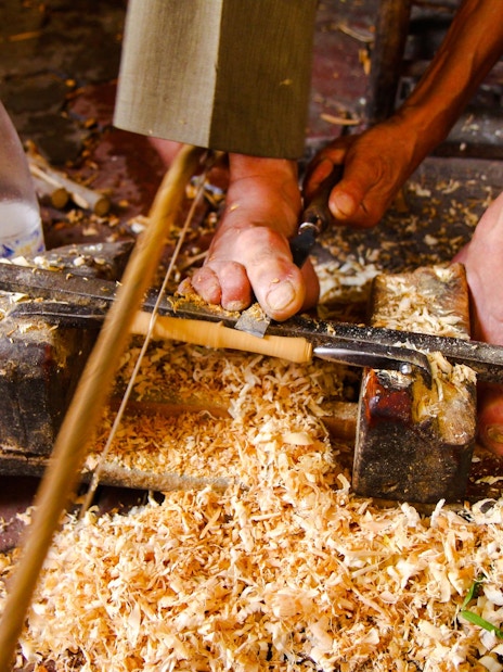Woodworker carving with feet in Marrakech workshop.