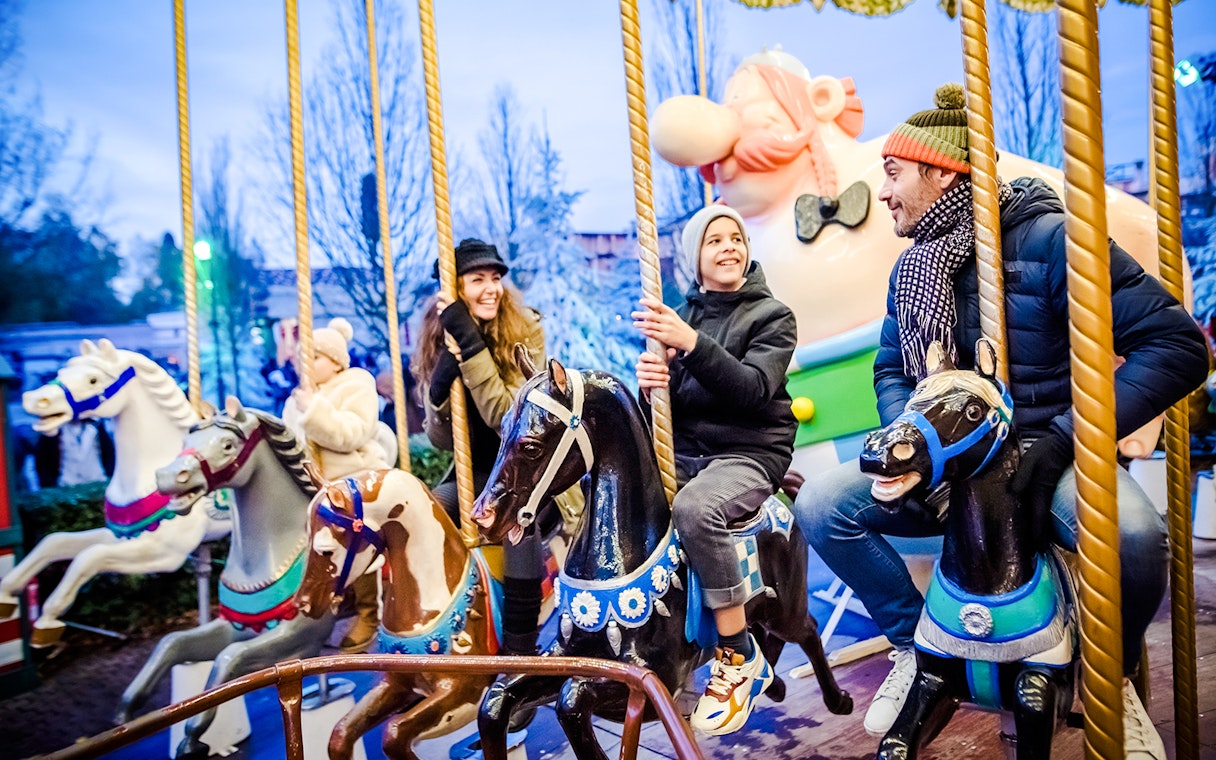 Family enjoying a carousel ride at Parc Asterix during Christmas celebrations.