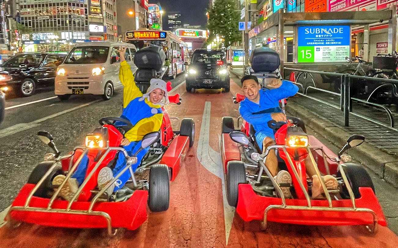 Go-kart riders in costumes driving through Asakusa, Tokyo at night.