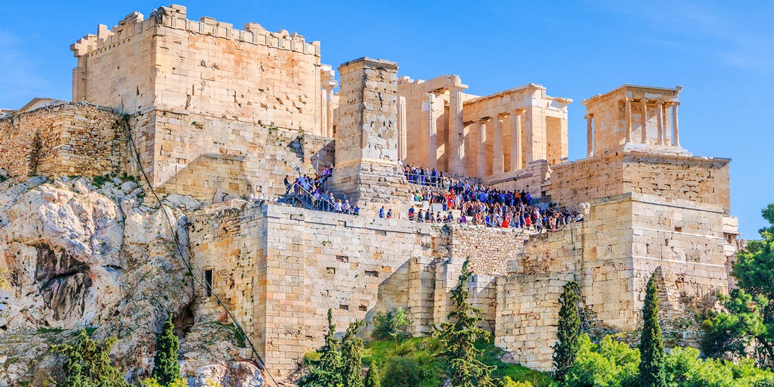 Propylaea entrance at Acropolis, Athens, with tourists exploring the ancient gateway.