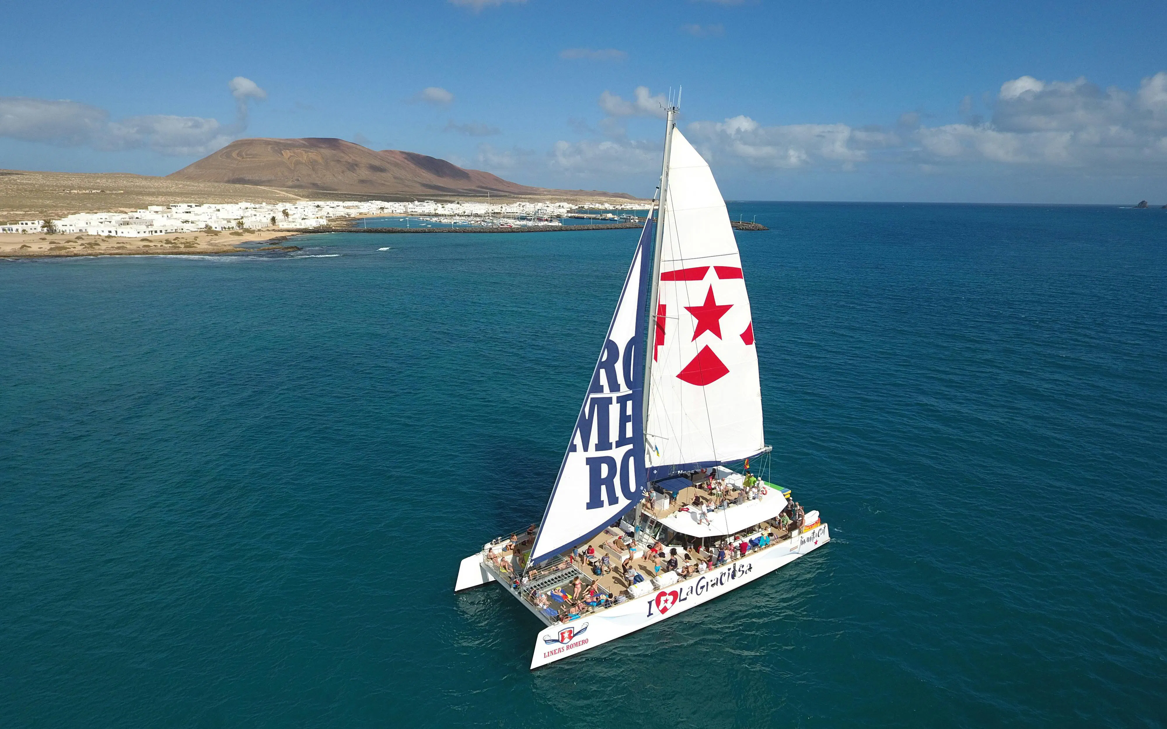 Catamaran sailing near La Graciosa Island with passengers enjoying the cruise.