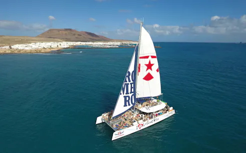 Catamaran sailing near La Graciosa Island with passengers enjoying the cruise.