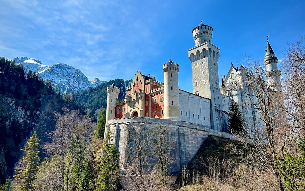 Neuschwanstein Castle with mountain backdrop, part of Munich train tour.