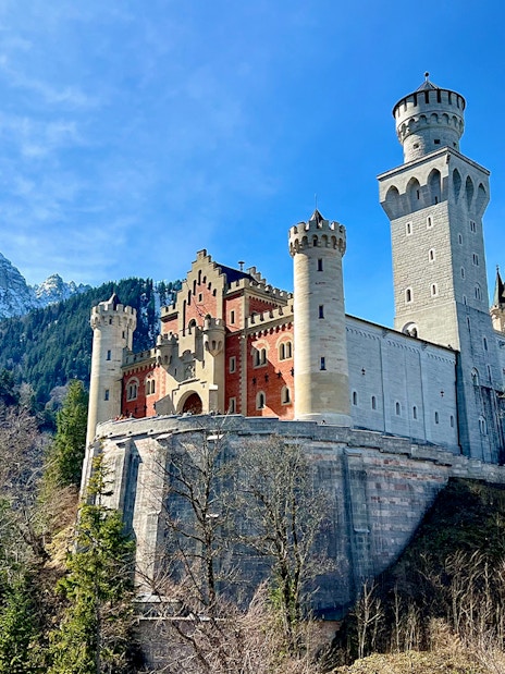 Neuschwanstein Castle with mountain backdrop, part of Munich train tour.