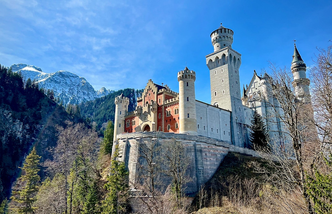 Neuschwanstein Castle with mountain backdrop, part of Munich train tour.