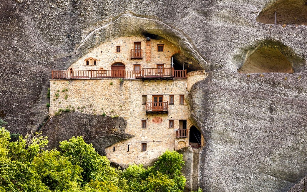 Hermit Caves dwelling carved into rock face with wooden balconies.