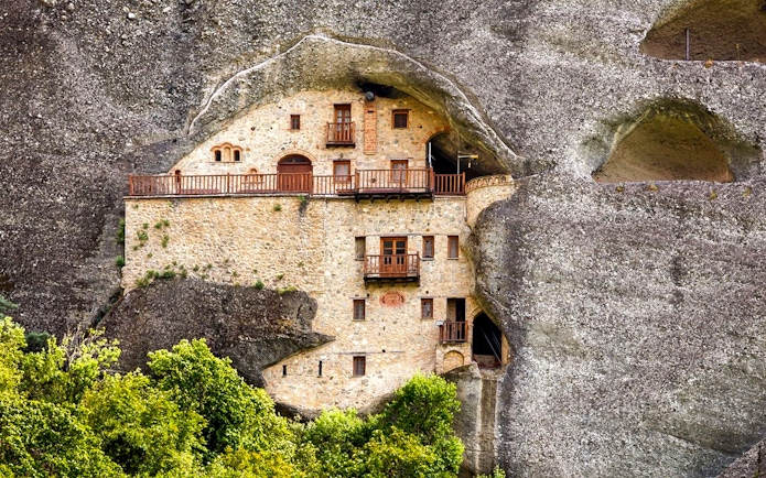 Hermit Caves dwelling carved into rock face with wooden balconies.