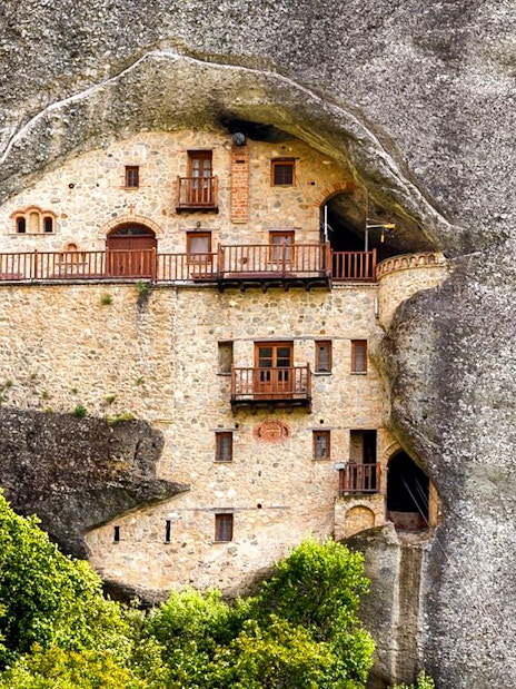 Hermit Caves dwelling carved into rock face with wooden balconies.
