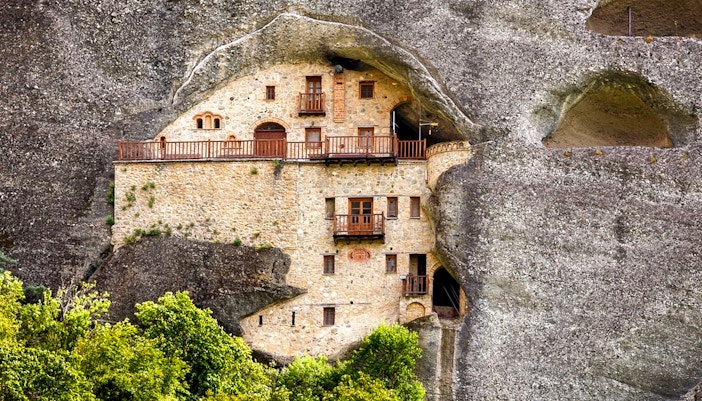 Hermit Caves dwelling carved into rock face with wooden balconies.