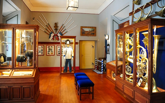 Cesky Krumlov Castle Museum interior with historical uniforms and musical instruments.