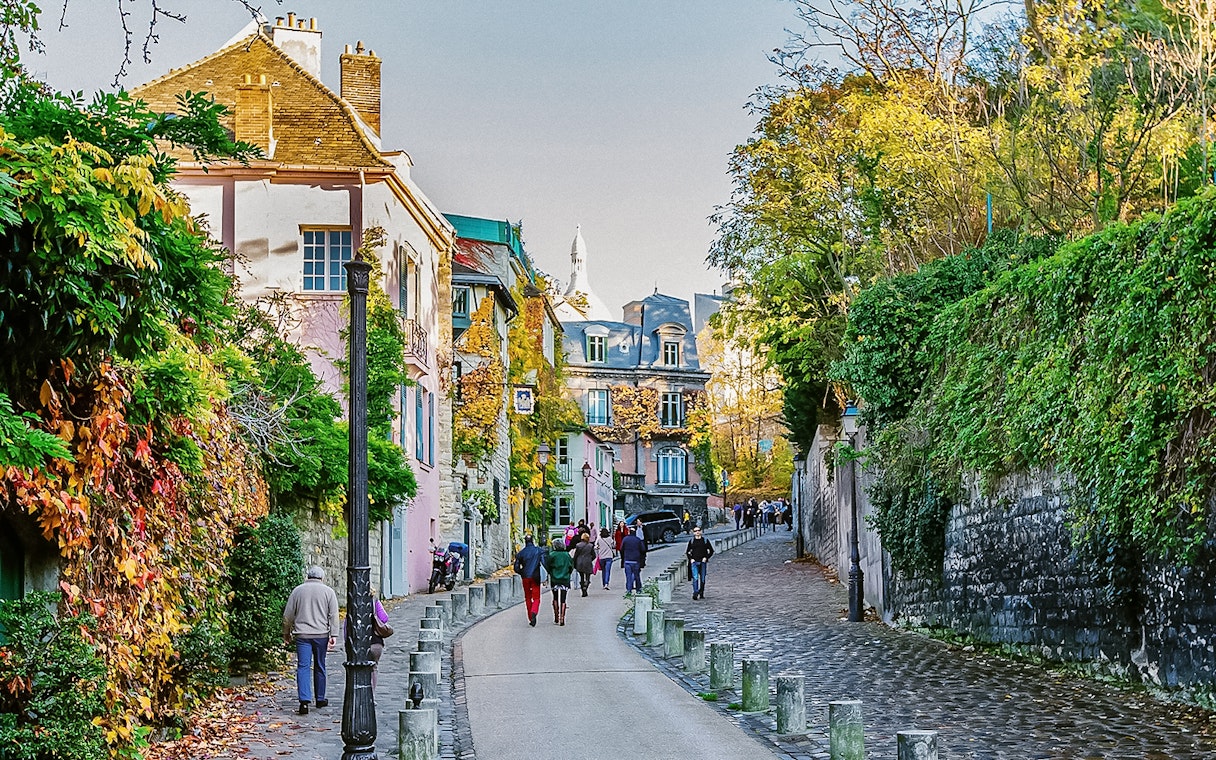 Montmartre street scene with colorful buildings and people walking, Paris.