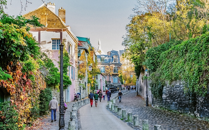 Montmartre street scene with colorful buildings and people walking, Paris.