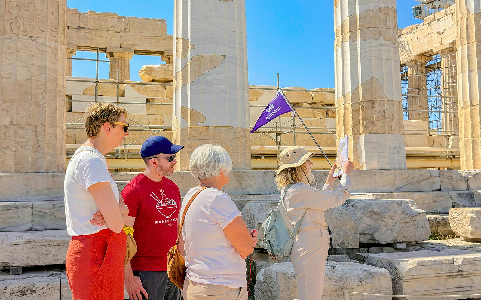 Tour group exploring the Acropolis in Athens with a guide holding a flag.
