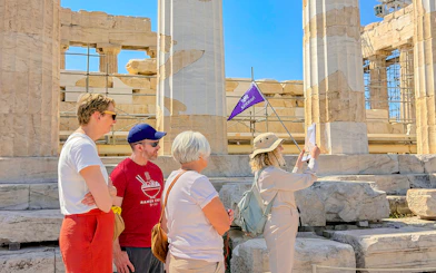 Tour group exploring the Acropolis in Athens with a guide holding a flag.