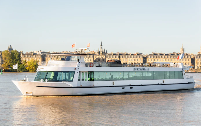 Bordeaux river cruise boat on the Garonne with cityscape in the background.
