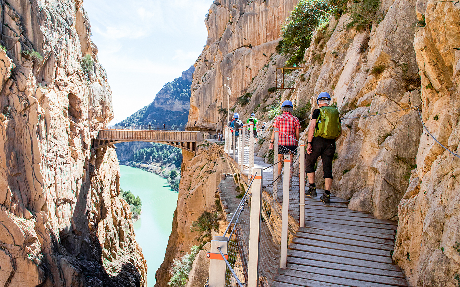 Hikers on Caminito del Rey trail in Málaga, Spain, walking along a cliffside path.