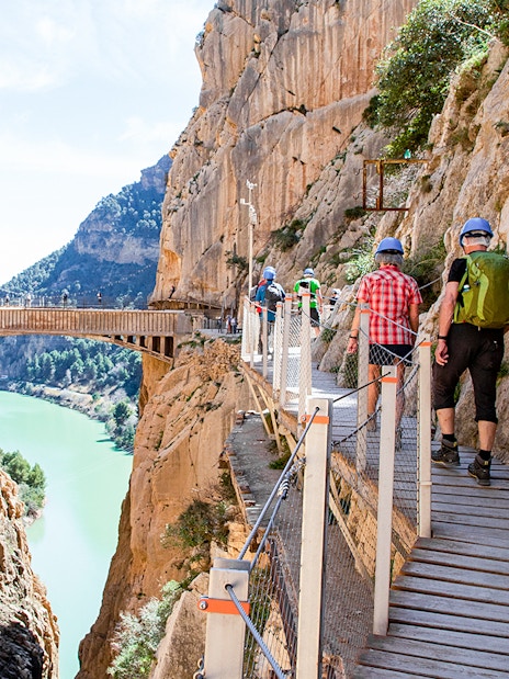 Hikers on Caminito del Rey trail in Málaga, Spain, walking along a cliffside path.