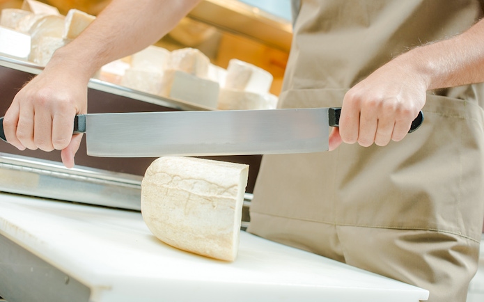 Server slicing cheese at Cheese Museum in Paris.