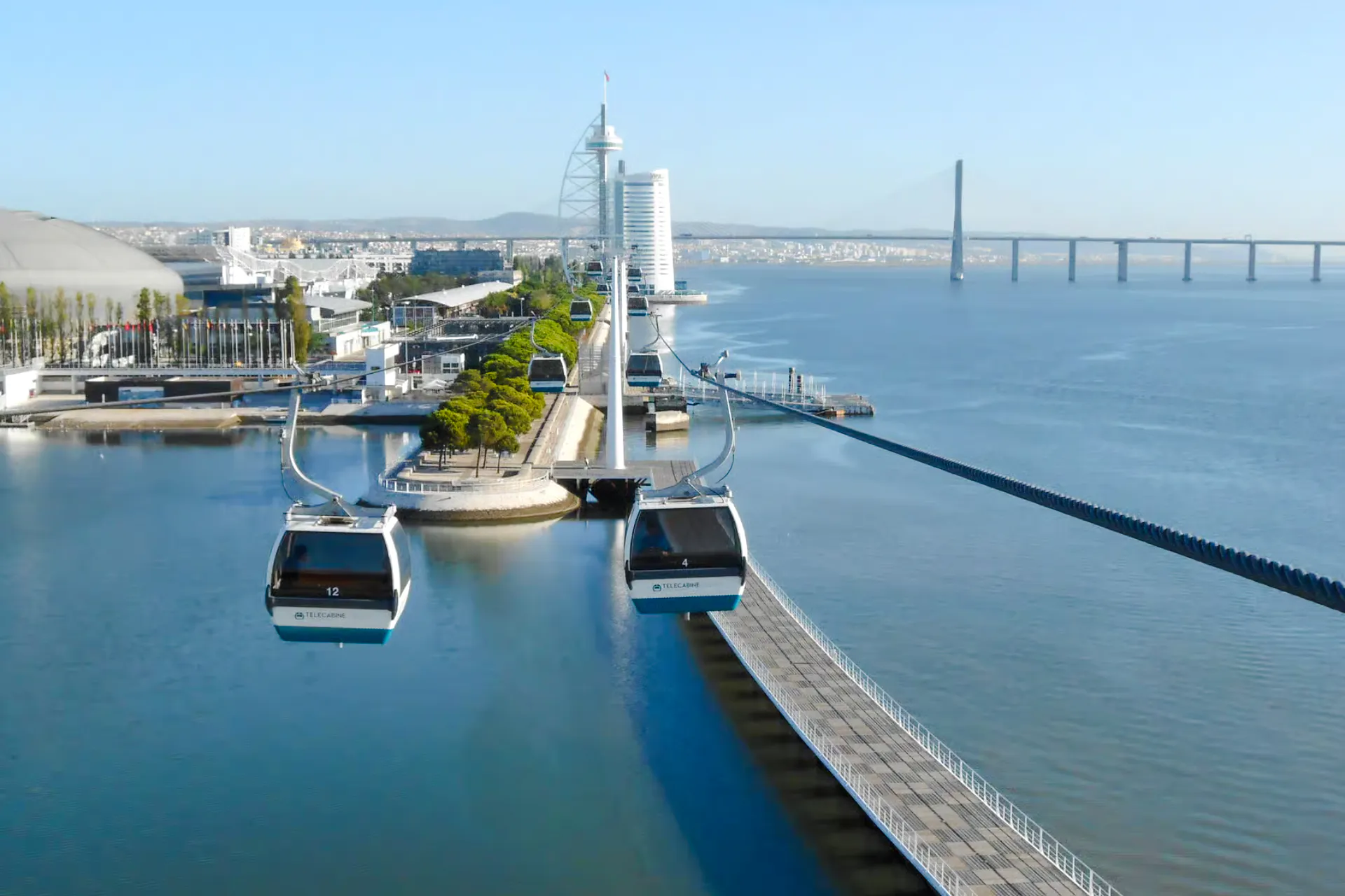 Lisbon cable cars over Tagus River with Vasco da Gama Bridge in the background.