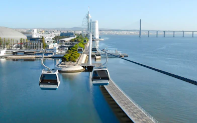 Lisbon cable cars over Tagus River with Vasco da Gama Bridge in the background.