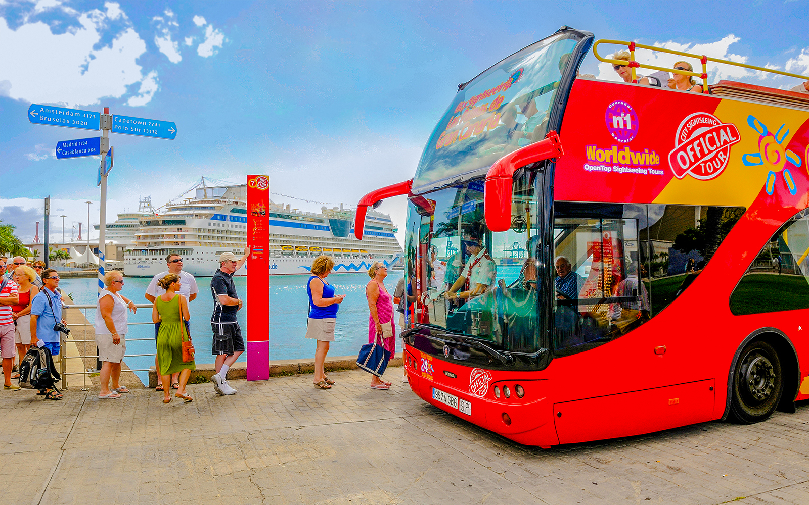 Hop-on hop-off bus at Las Palmas de Gran Canaria port with tourists boarding.