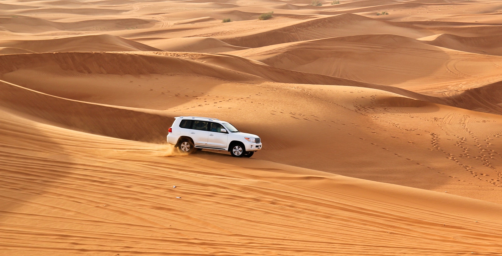 SUV driving over sand dunes during a desert safari.