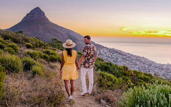 Couple watching sunset at Lion's Head near Table Mountain, Cape Town, South Africa.
