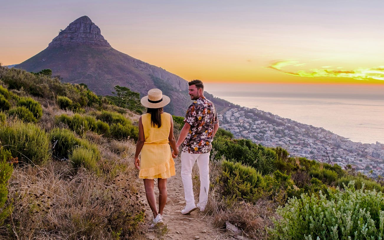 Couple watching sunset at Lion's Head near Table Mountain, Cape Town, South Africa.