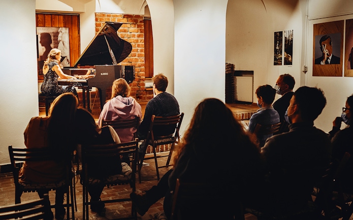 Pianist performing Chopin at Old Town recital with audience seated.
