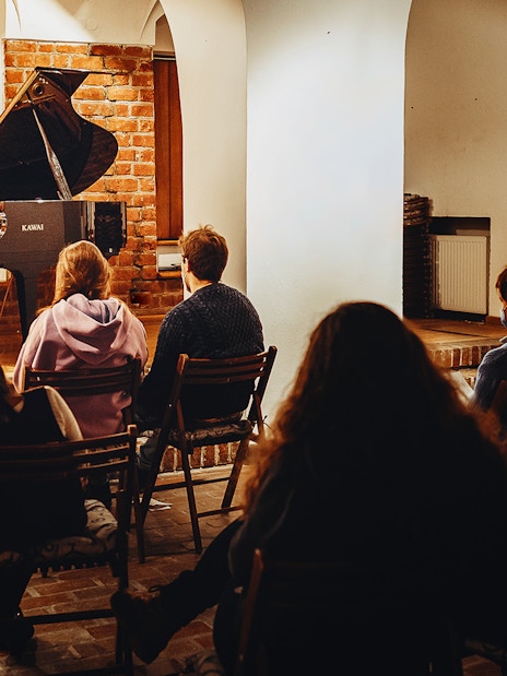 Pianist performing Chopin at Old Town recital with audience seated.
