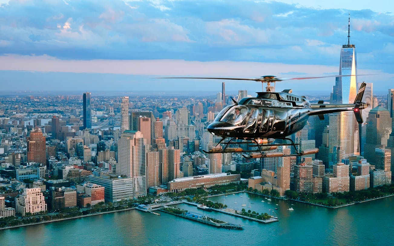 Helicopter flying over New York City skyline with One World Trade Center in view.