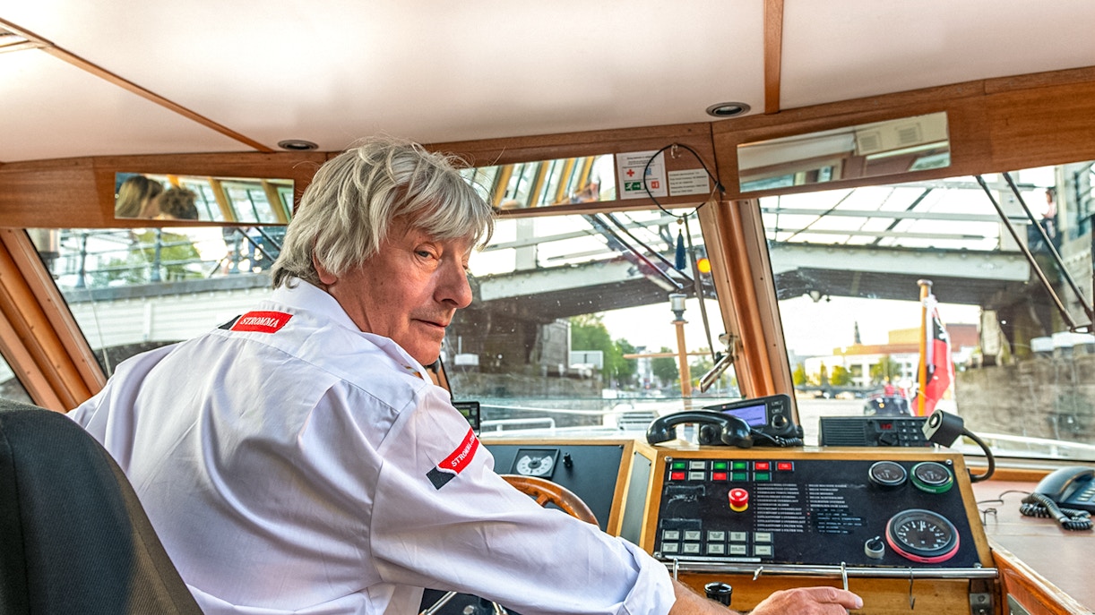Boat captain steering during Amsterdam city centre cruise.