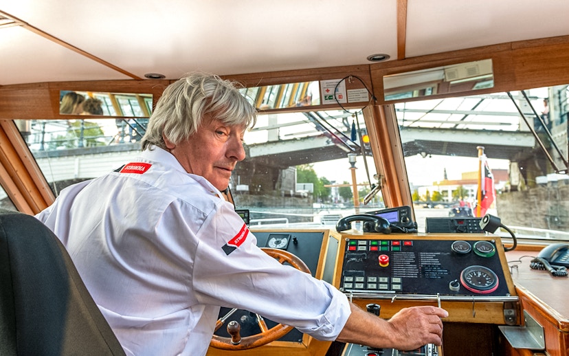 Boat captain steering during Amsterdam city centre cruise.