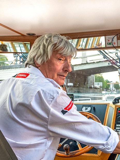 Boat captain steering during Amsterdam city centre cruise.