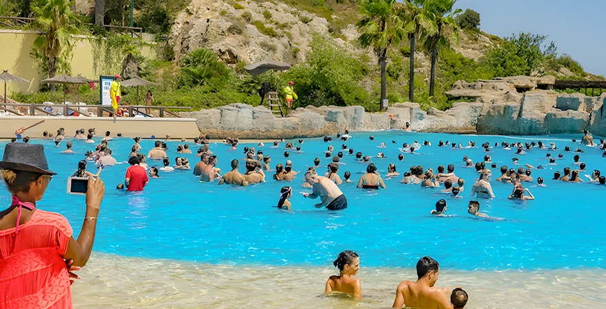 Visitors enjoying the wave pool at Aquopolis Cullera water park, Spain.