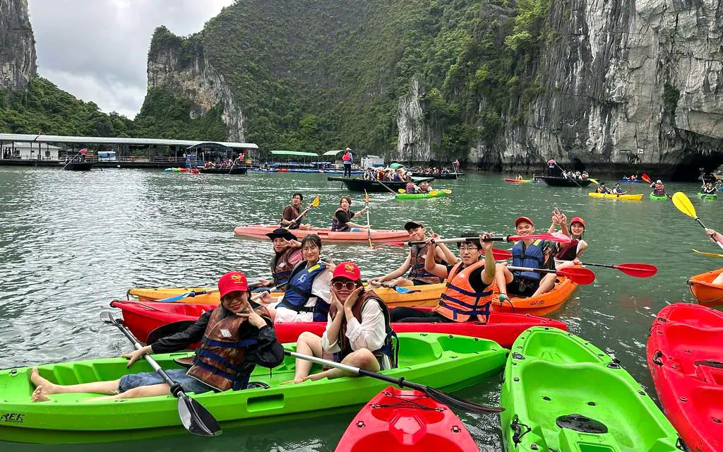 Kayakers enjoying Ha Long Bay on La Casta Day Cruise with limestone cliffs in the background.