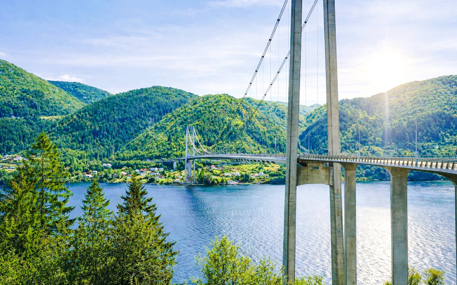 Osteroy Bridge spanning over fjord with lush green hills in Bergen, Norway.