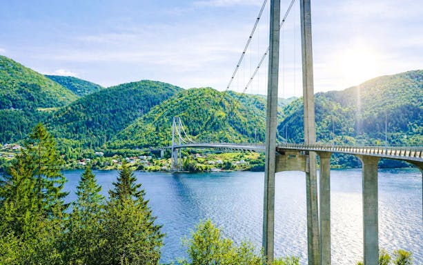 Osteroy Bridge spanning over fjord with lush green hills in Bergen, Norway.