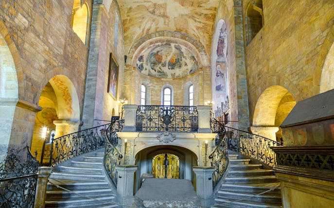 Basilica of St George interior with ornate staircase and frescoed ceiling.