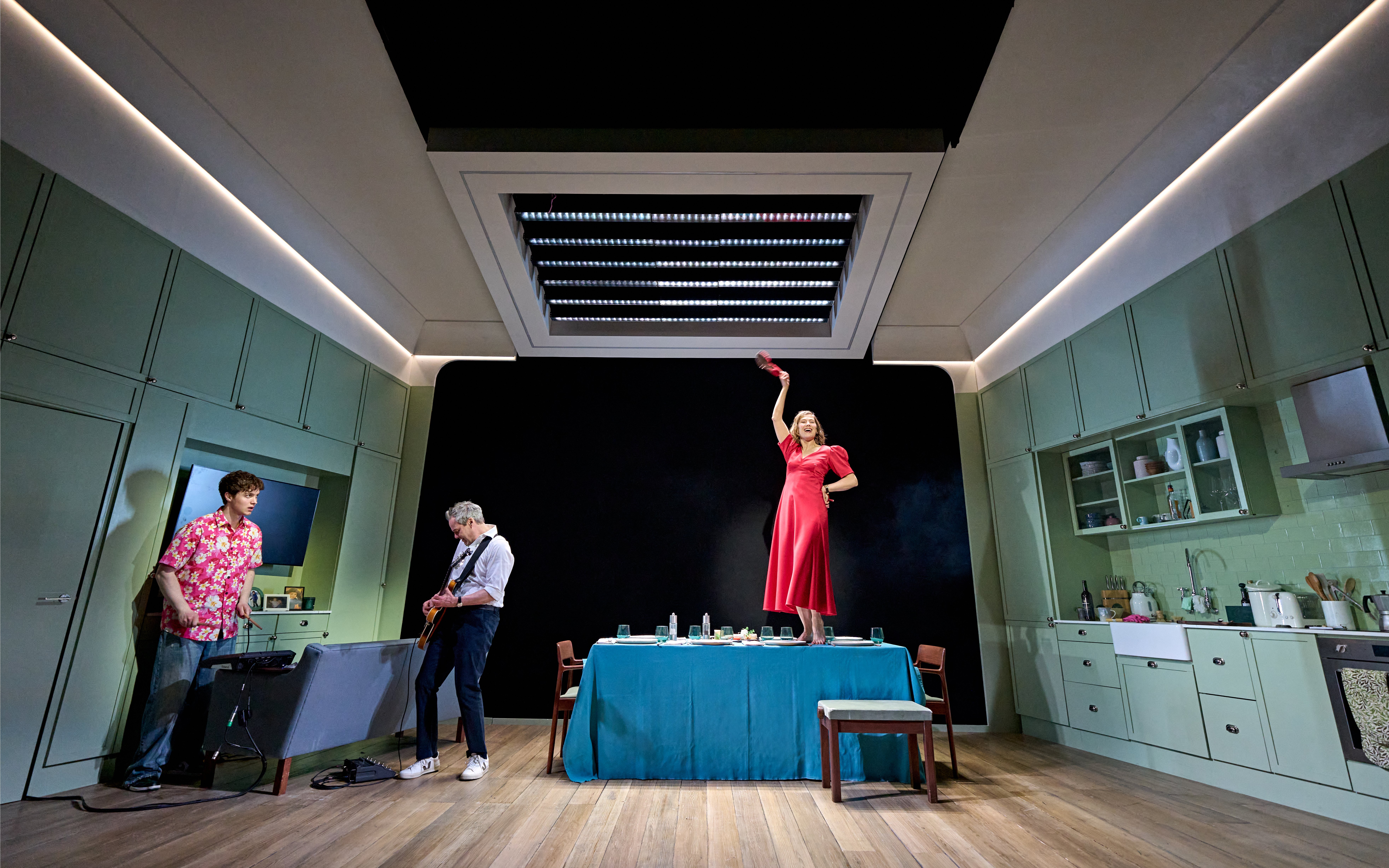 Actors performing a scene in a modern kitchen set during "Inter Alia" at West End.